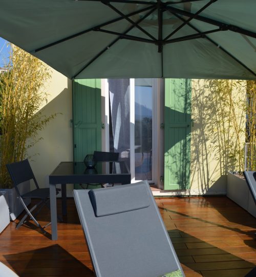 La terrasse avec sa table, chaises longues et grand parasol